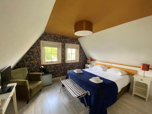 ein Schlafzimmer mit einem Bett, einem Stuhl und einem TV in der Unterkunft Recreatiepark Wiringherlant in Hippolytushoef