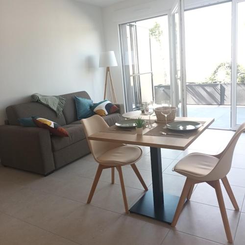 a living room with a table and chairs and a couch at Cosy Diem Cap d'Agde in Cap d'Agde