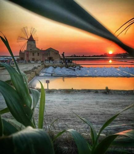 a sunset over a beach with a windmill at B&B da Giovy in Marsala
