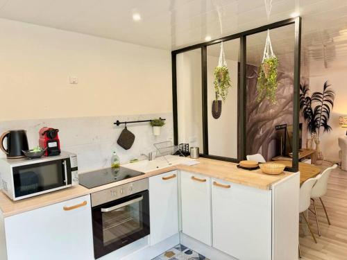 une cuisine avec des armoires blanches, un évier et un micro-ondes dans l'établissement Le Vendays Reims plein de charme, à Reims