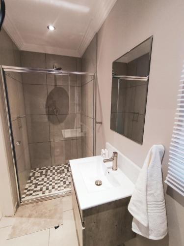 a bathroom with a shower and a sink at Palmera Guest House in Krugersdorp