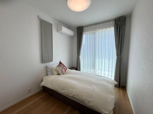 Un dormitorio con una cama con una ventana grande. en Akikawa Koshi 5, en Yuge