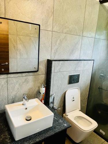 a bathroom with a sink and a toilet and a mirror at Haven Stay Manor in Kotamangalam