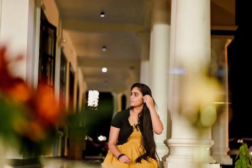 a woman in a yellow dress sitting in a hallway at Haven Stay Manor in Kotamangalam