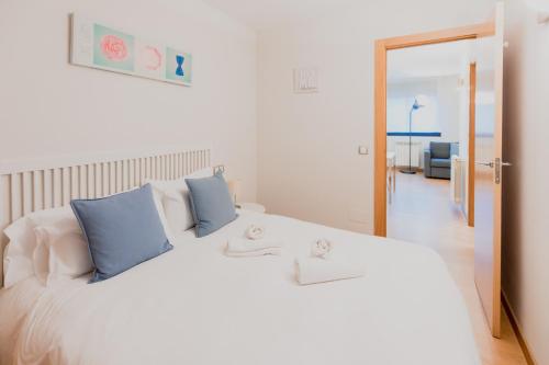 een slaapkamer met een groot wit bed met blauwe kussens bij Confort Escaldes HUT 5003 - HUT 7755 in Andorra la Vella
