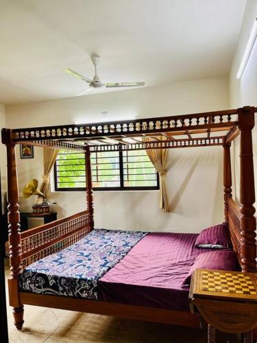 a wooden canopy bed in a room with a window at Haven Stay Manor in Kotamangalam