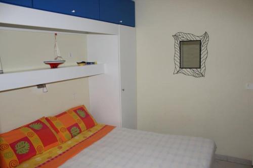 Cette chambre blanche comprend un lit et un miroir. dans l'établissement 2 bedroom apartment with large terrace, à Théoule-sur-Mer