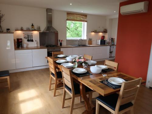 a kitchen with a wooden table with chairs and a kitchen with white cabinets at Maison La Chapelle Bellevue in Saint-Solve