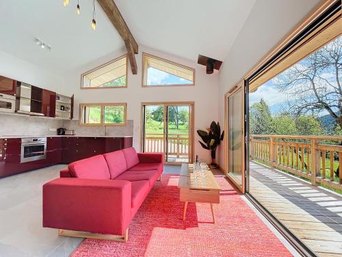 un salon avec un canapé rouge et un balcon dans l'établissement Chalet Bahia - Les Gets - secteur le Lavay, aux Gets