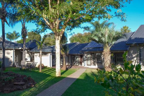 a house with a yard with palm trees at Palmera Guest House in Krugersdorp
