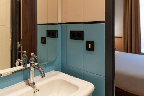 a bathroom with a white sink and blue tiles at Hotel Terminus Lyon in Paris