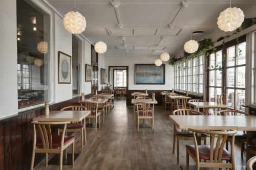 un restaurante con mesas, sillas y ventanas en Hotel Ærø en Svendborg