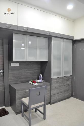 a kitchen with white cabinets and a table and a chair at Kalpattaru Sadan Luxurios 3BHK in Pune