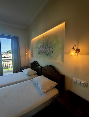 two beds in a hotel room with a painting on the wall at Xanemos Studios in Skiathos