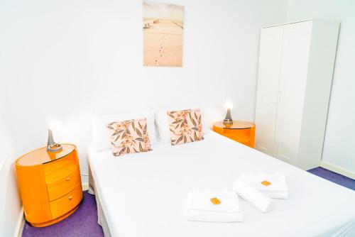 a white bedroom with two beds and two night stands at Apartment 22 Burswood in Perth