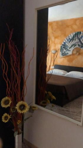 a mirror in a bedroom with a bed and flowers at Affittacamere Selene in Sanremo