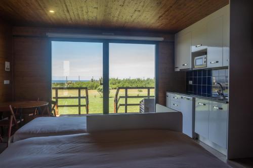 a room with two beds and a kitchen with a large window at PenichePraia - Bungalows, Campers & SPA in Peniche