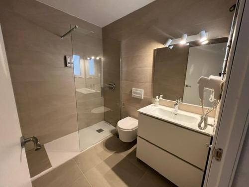 bagno con doccia, lavandino e servizi igienici di Hostal Cala Moli a Cala Tarida