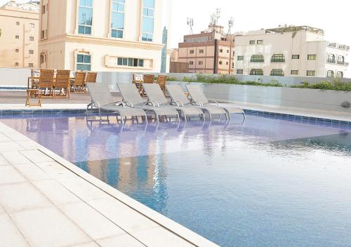 a row of chairs sitting next to a swimming pool at Farhan Tower in Juffair