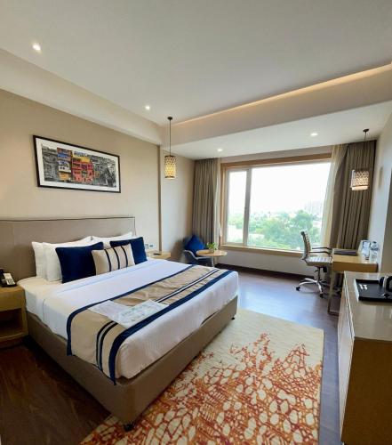a bedroom with a large bed and a large window at The Fern Residency Sarnath in Varanasi