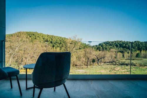 a chair and a table in a room with a window at Pachán Dehesa Boyal in Cuenca
