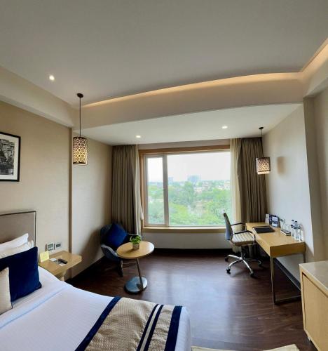 a hotel room with a bed and a large window at The Fern Residency Sarnath in Varanasi