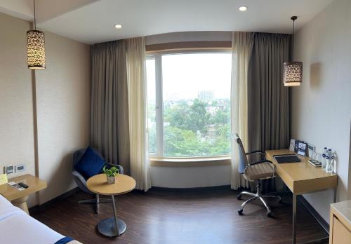 a hotel room with a bed and a desk and a window at The Fern Residency Sarnath in Varanasi