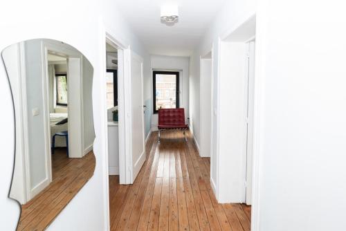 a hallway of a home with white walls and wood floors at Townhouse Tongeren Center - Featured in Designbook in Tongeren
