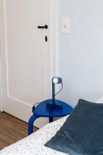 a blue stool next to a bed in a room at Townhouse Tongeren Center - Featured in Designbook in Tongeren