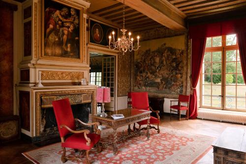 a room with a fireplace and a table and chairs at Le château de Bonnemare - Bed and breakfast in Radepont