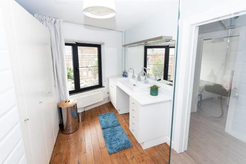 a white bathroom with a sink and a mirror at Townhouse Tongeren Center - Featured in Designbook in Tongeren