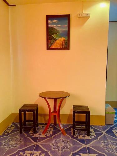 a table and two stools in a room at Baan Klong House in Baan Khai