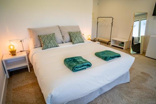 a large white bed with two green pillows on it at Pachán Dehesa Boyal in Cuenca