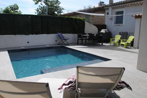 une piscine avec deux chaises et une table dans l'établissement Maison de village dans Luberon avec piscine privée, à Villelaure