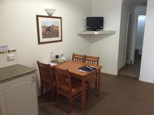 a room with a table and chairs and a television at Criterion Hotel-Motel Rockhampton in Rockhampton