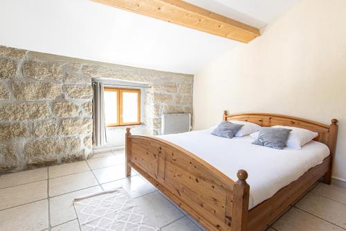 a bedroom with a wooden bed in a stone wall at L'incudine in Sartène