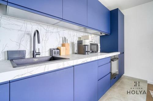 une cuisine avec des armoires bleues et un évier dans l'établissement À deux pas de Paris - Le Convivial - 105MB, à Rueil-Malmaison