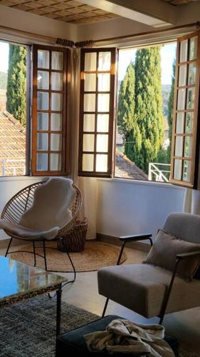 - un salon avec deux chaises et deux fenêtres dans l'établissement Magnifique maison provençale haut standing avec piscine, jardins, garages fermés, à Sablet