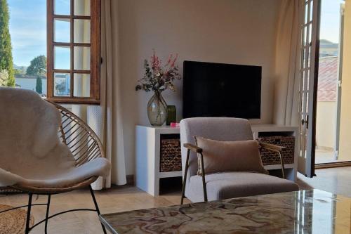 un salon avec deux fauteuils et une télévision dans l'établissement Magnifique maison provençale haut standing avec piscine, jardins, garages fermés, à Sablet