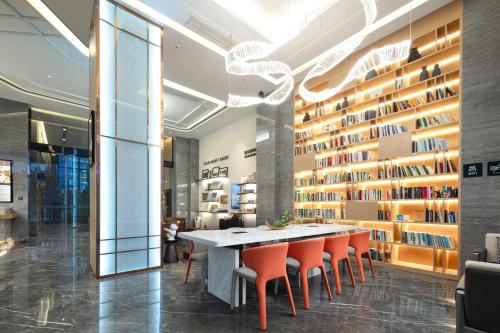a dining room with a long table and orange chairs at Atour Hotel Changhong Avenue in Jiujiang