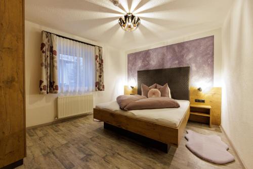 a bedroom with a bed and a chandelier at Apartmenthaus Goldeck in Ried im Oberinntal
