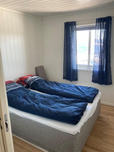 a bedroom with a bed with blue sheets and a window at Voss Resort self-service apartments in Skulestadmo