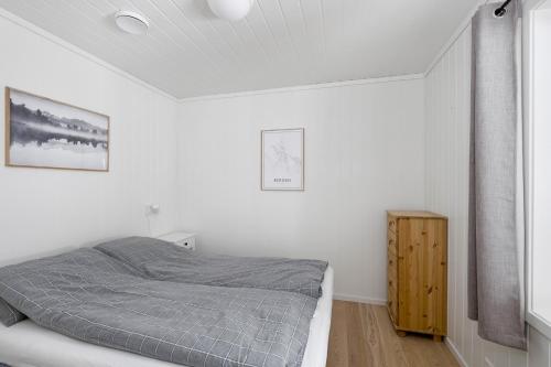 a white bedroom with a bed and a wooden cabinet at Voss Resort self-service apartments in Skulestadmo