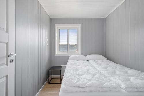 a white bedroom with a bed and a window at Voss Resort self-service apartments in Skulestadmo