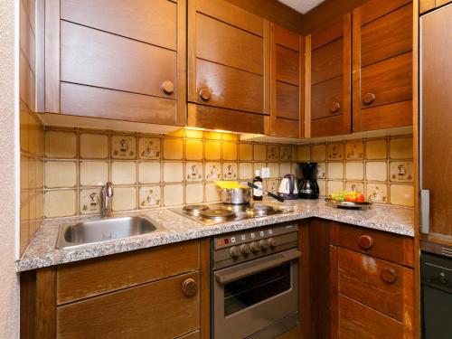 Una cocina con gabinetes de madera y un fregadero. en Apartment Residenza Chesa Margun 23-1 by Interhome, en Surlej