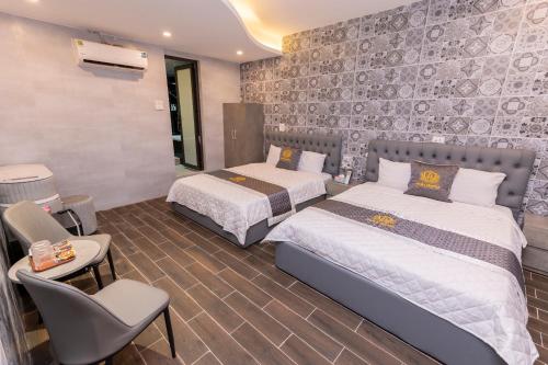 a bedroom with two beds and a chair in it at Khách sạn Hera Hotel in Hà Ðông