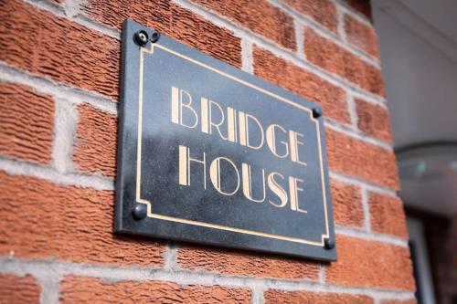 a sign for a bridge house on a brick wall at Bridge House Apartments - Free Parking in Shottery
