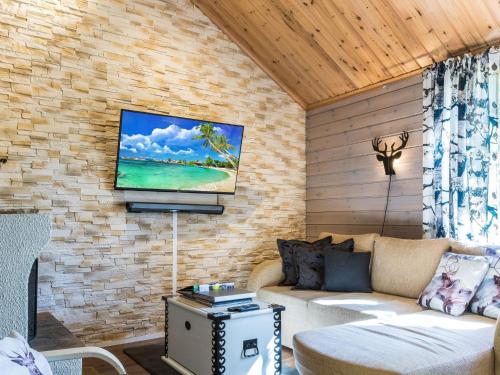 a living room with a couch and a tv on a brick wall at Holiday Home Isonparit b3 by Interhome in Ylläsjärvi