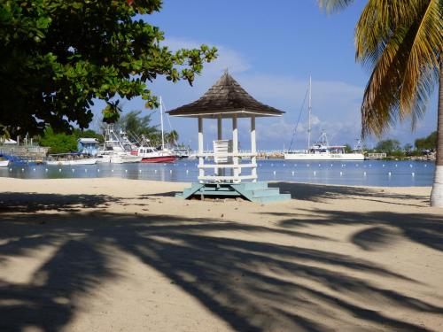 a chair on a beach with boats in the water at Beach Studio 6 in Ocho Rios