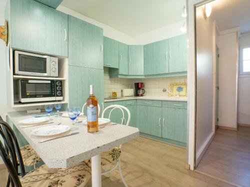 una cocina con armarios verdes y una mesa con copas de vino en Apartment Le Lido-3 by Interhome, en Les Lecques